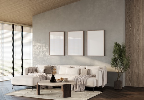 Modern minimalist living room with a light beige sectional sofa, wooden coffee table, neutral throw blankets, and decorative accents.